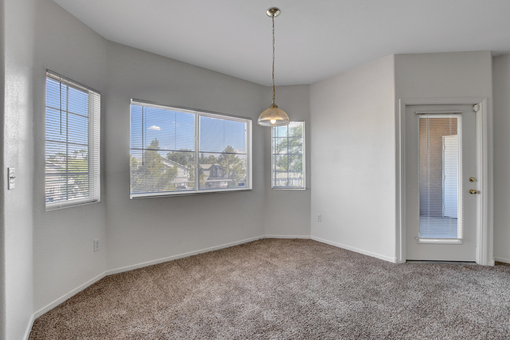 an empty living room with three windows and a door