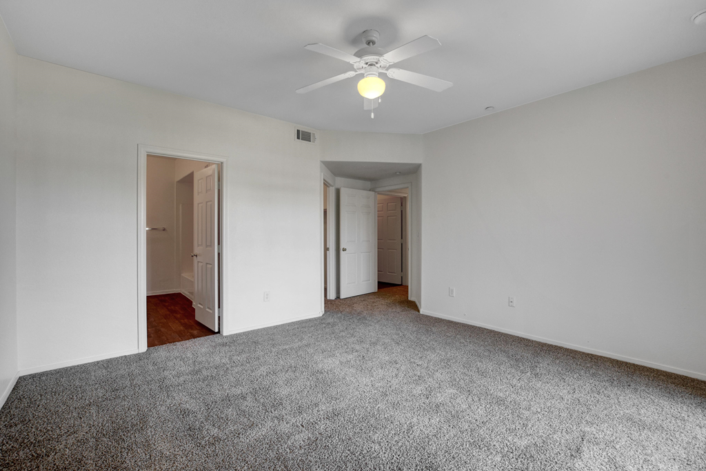 an empty living room with white walls and a ceiling fan