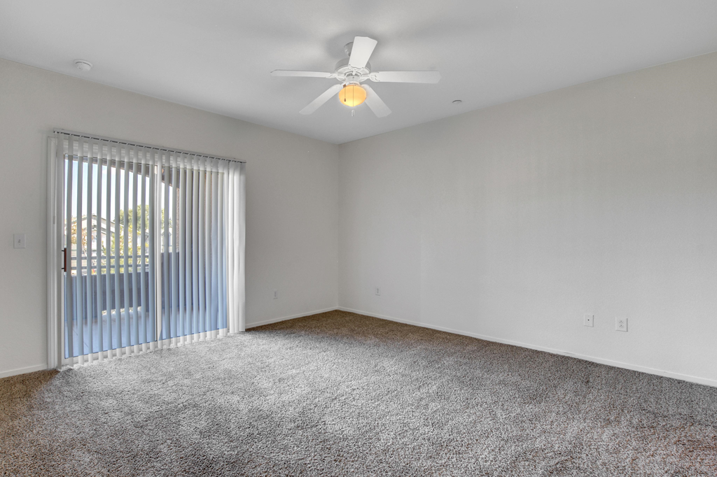 an empty living room with a ceiling fan and a window
