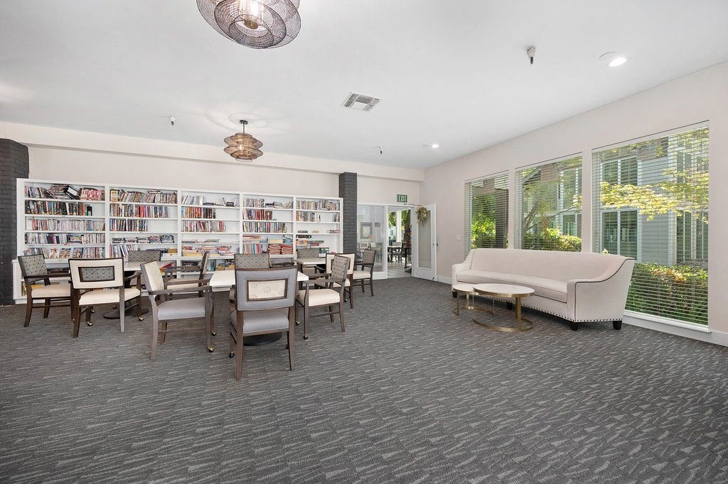 a library with a couch and chairs and a table and chairs in the middle of the room