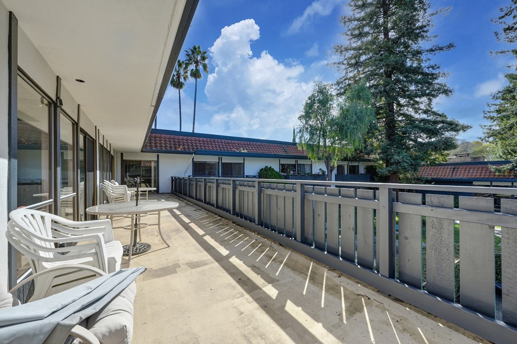 a balcony with white chairs and tables and a building in the background