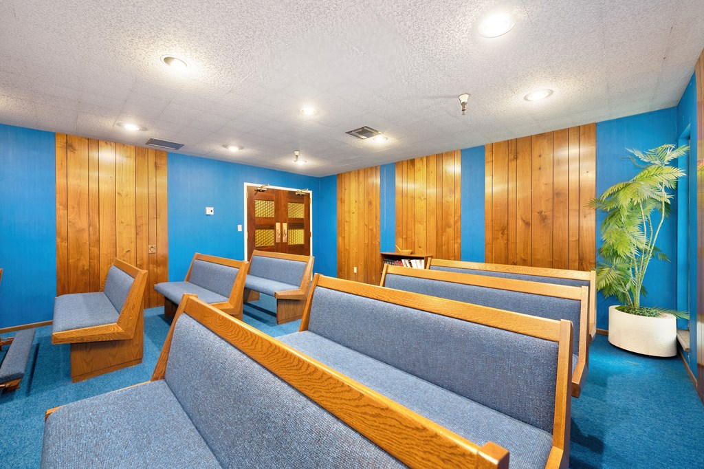 a waiting room with blue couches and chairs and a potted plant