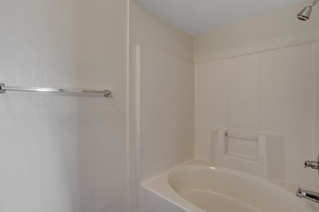a white bathroom with a tub and shower and a sink