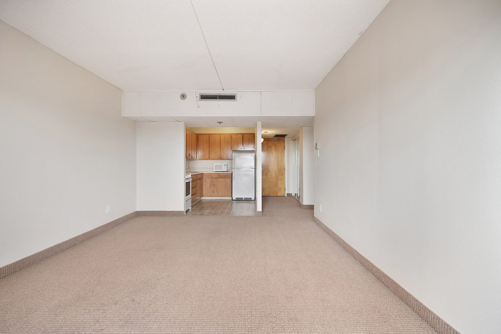 an empty living room and kitchen with white walls and carpet