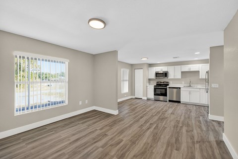 A spacious living room with a kitchen in the background.