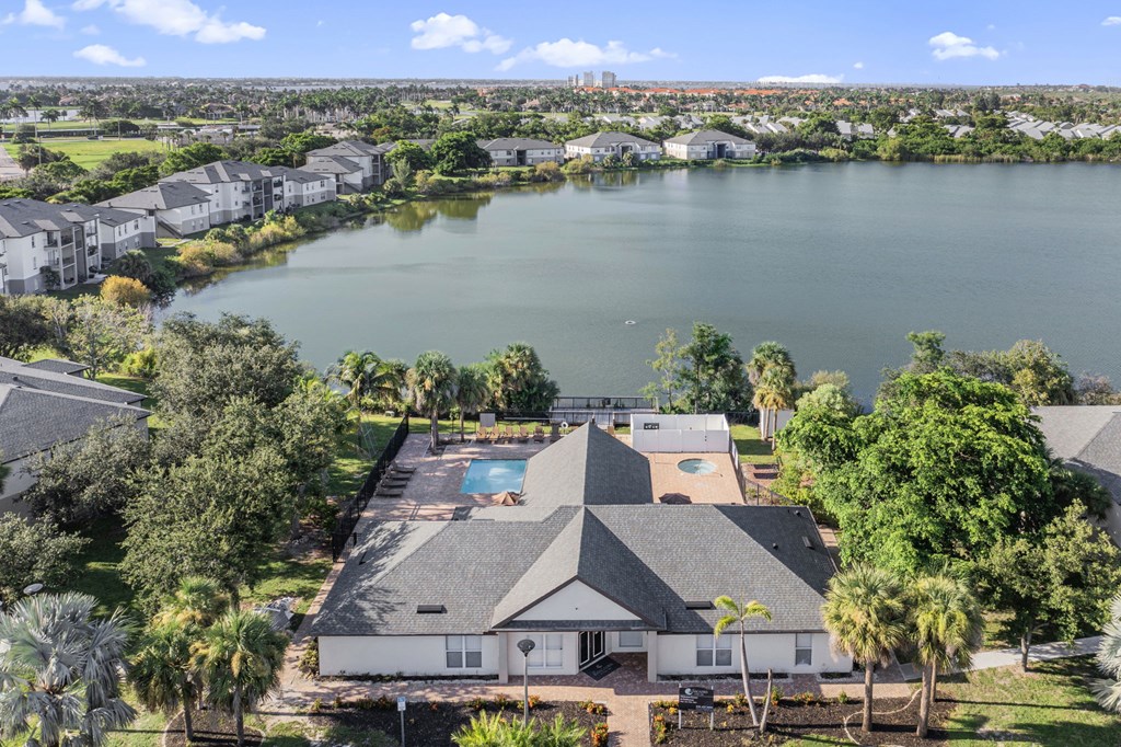 A large house with a pool in the middle of a lake surrounded by trees.