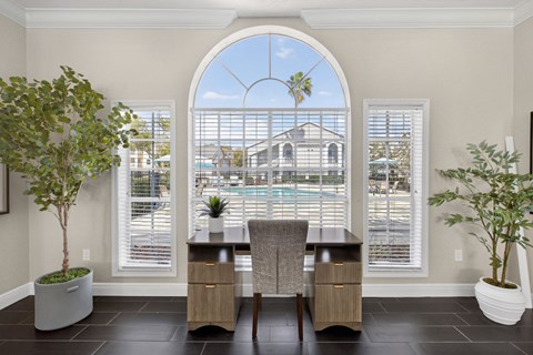 Office workspace with arched window and pool view at The Ivy at Gatehouse Apartments, Florida