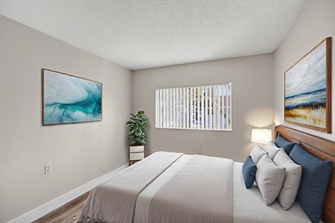 A bedroom with a large bed and two framed pictures on the wall.