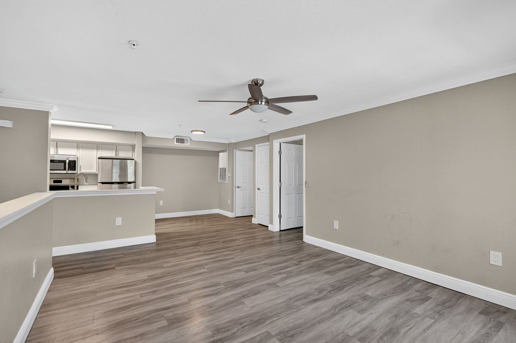 A room with a ceiling fan and wooden flooring.