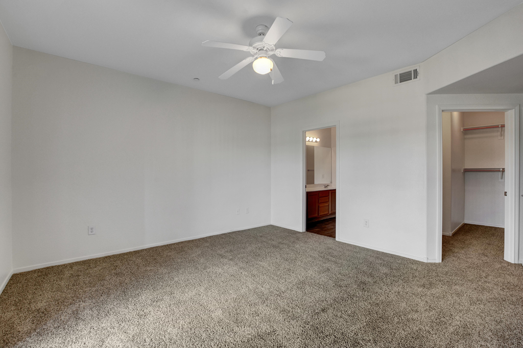 an empty living room with white walls and a ceiling fan