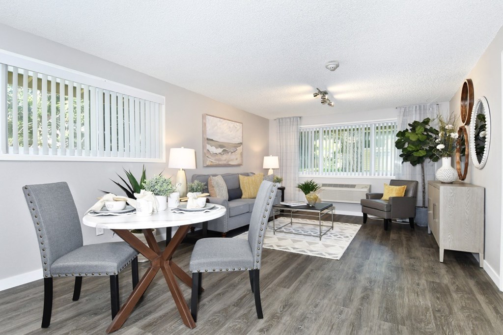 A dining room with a round table and grey chairs.