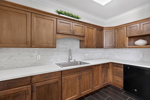 A kitchen with wooden cabinets and a black dishwasher.