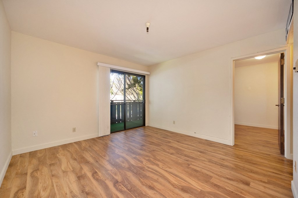 a living room with a door to a balcony and a hard wood floor