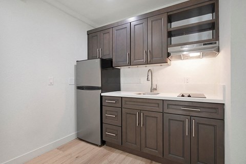 a kitchen with dark cabinets and a stainless steel refrigerator
