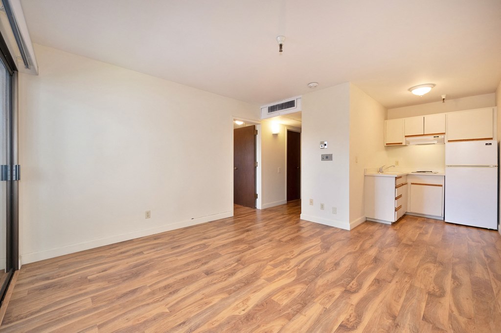 a living room and kitchen with a wood floor and white appliances