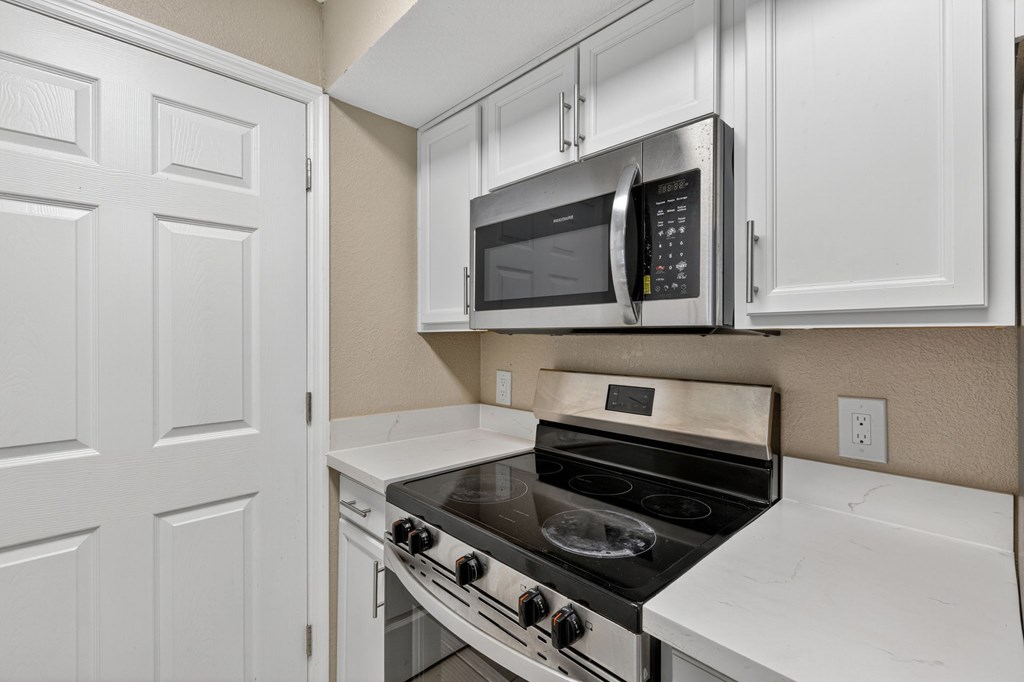 A kitchen with a stove, oven, microwave, and cabinets.