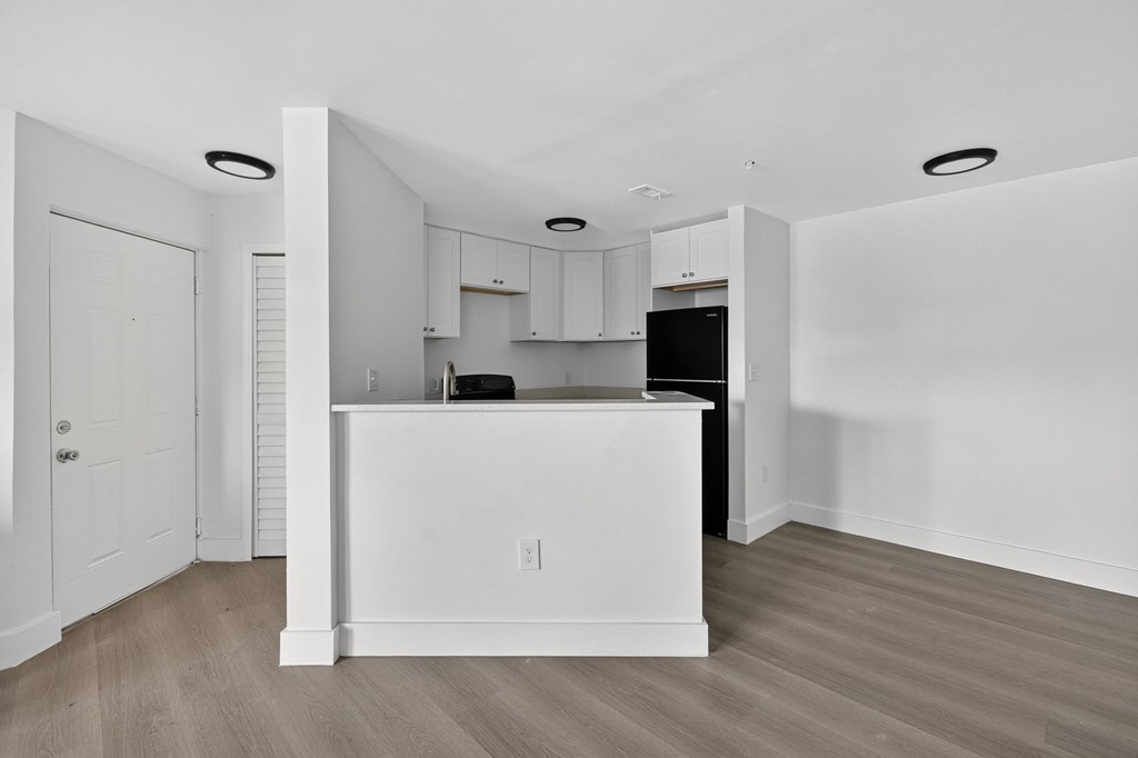 A kitchen with white cabinets and a black fridge.