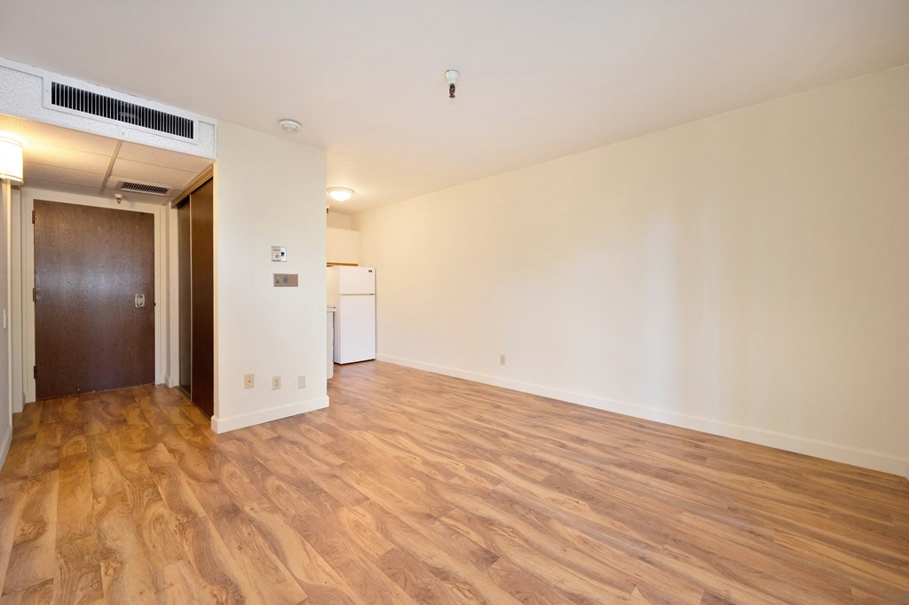 a living room with wood flooring and a door to a kitchen