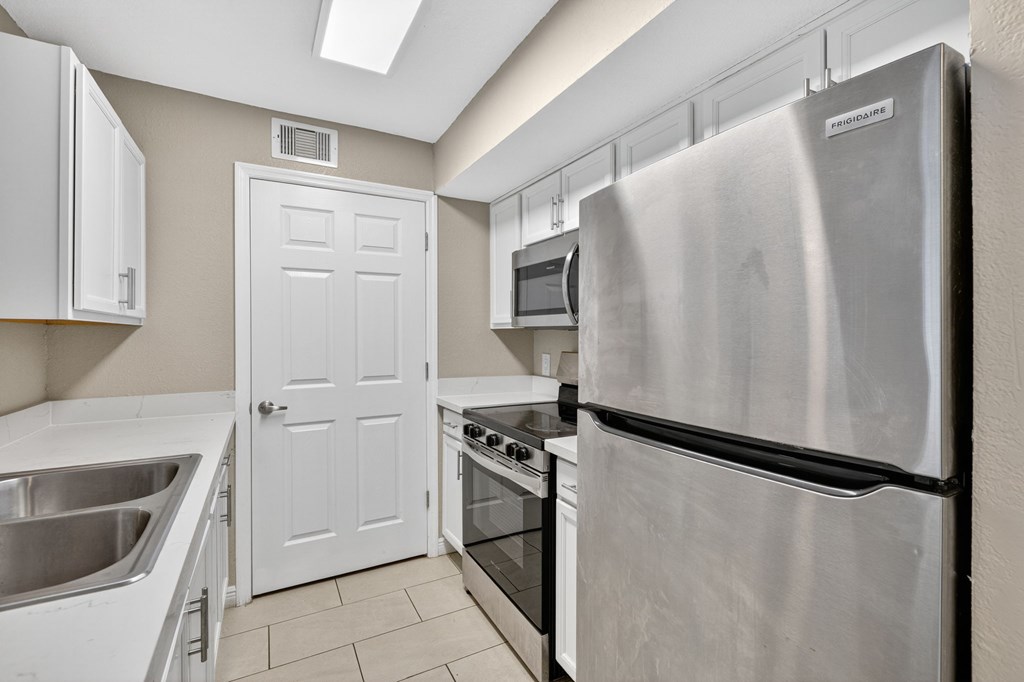 A kitchen with a stainless steel refrigerator, oven, and microwave.
