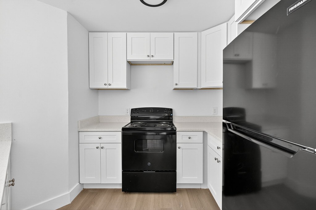 A black oven and dishwasher in a kitchen with white cabinets.