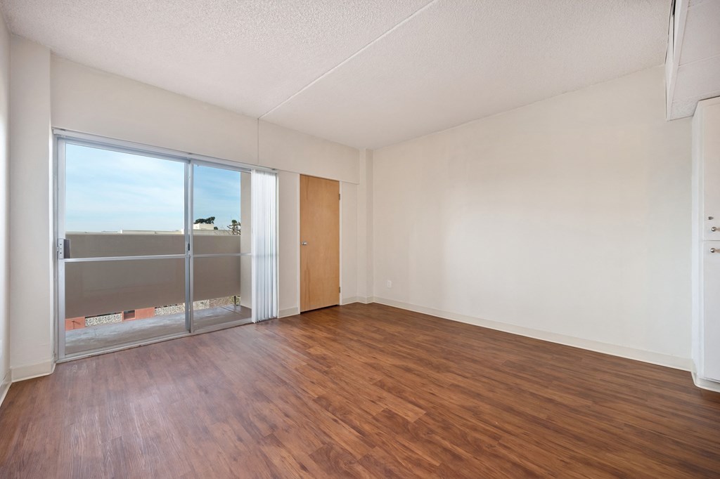 an empty living room with wood flooring and sliding glass doors