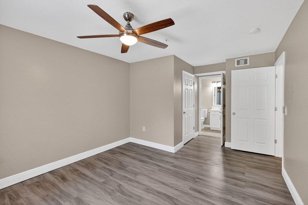 A room with a ceiling fan and wooden flooring.