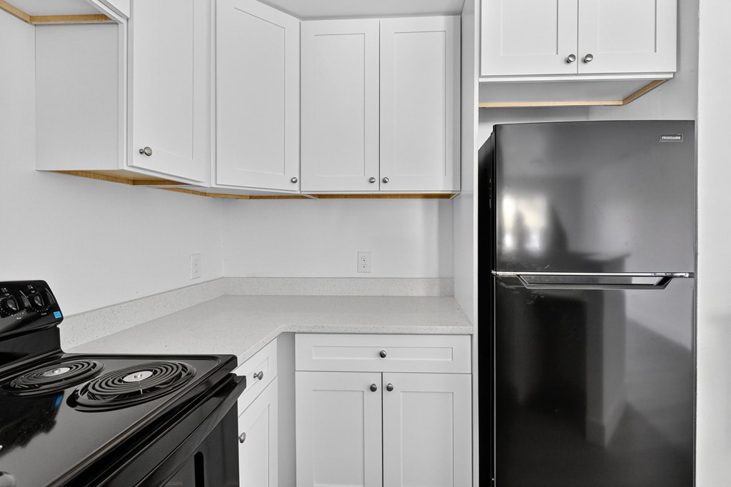 A black stove top oven sits under a white cabinet in a kitchen.