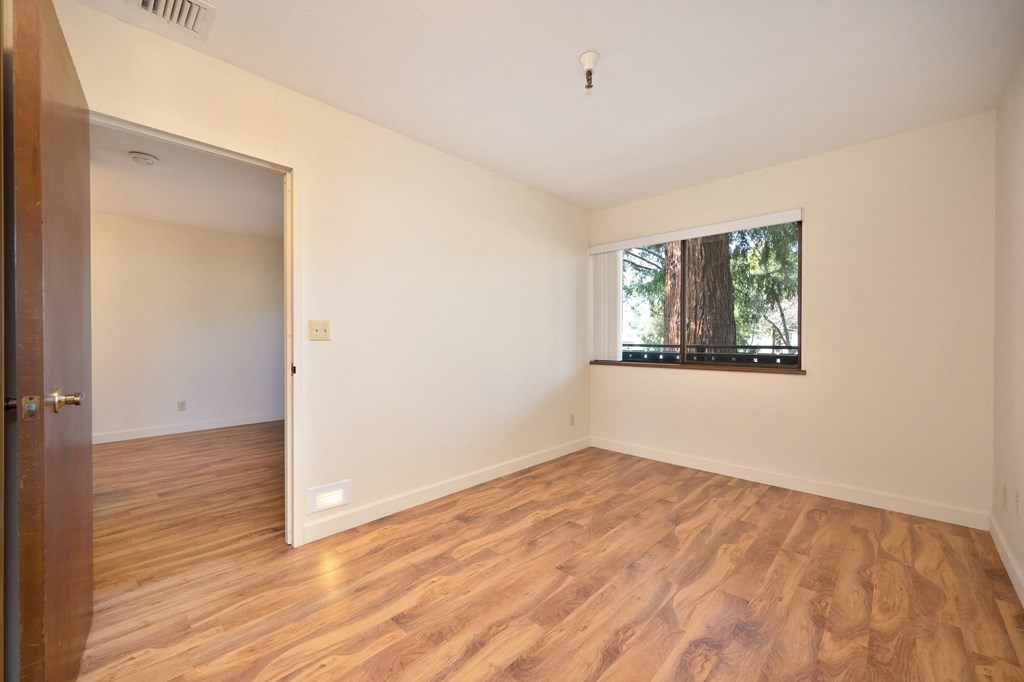 an empty living room with a window and wood flooring