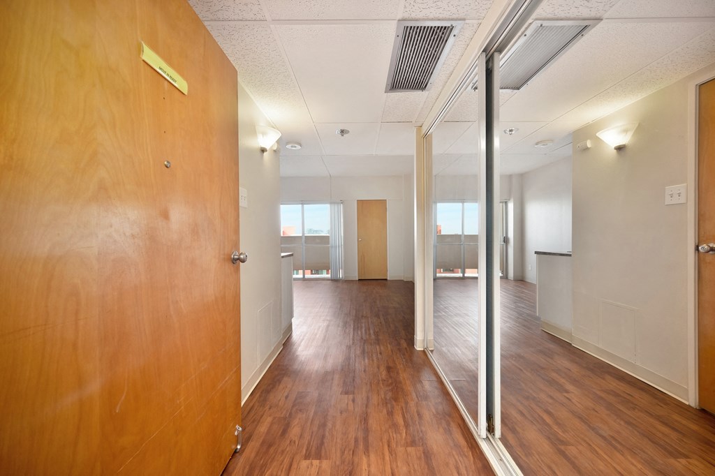 an empty hallway with wooden floors and a glass door