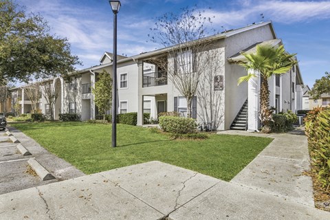 A street lamp stands in front of a building with a white facade and a green lawn.