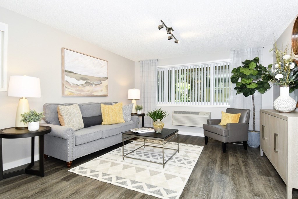 A living room with a grey couch, a coffee table, and a painting on the wall.
