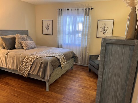 A bedroom with a bed, a chair, and a cabinet.