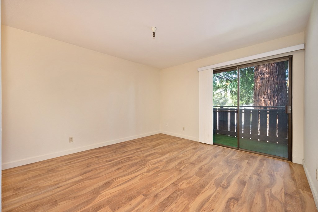 an empty living room with a sliding glass door to a backyard