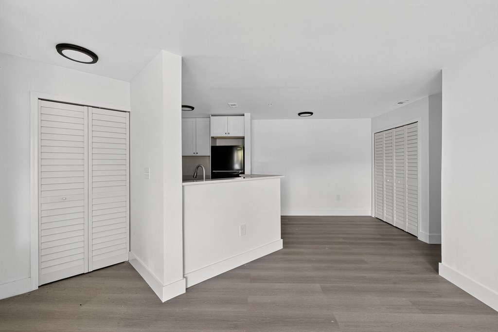 A white kitchen with a bar counter and a refrigerator.
