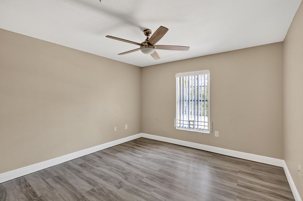 A room with a ceiling fan and a window with blinds.