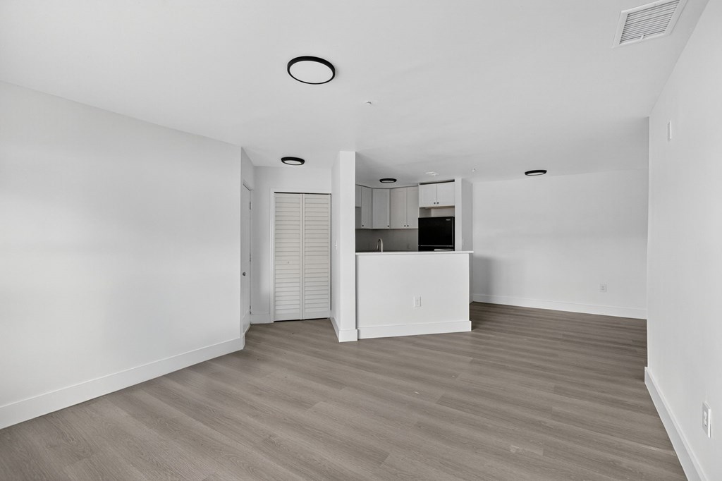 A spacious room with wooden flooring and white walls.
