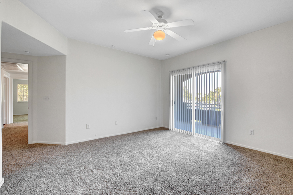 an empty living room with a ceiling fan and a window