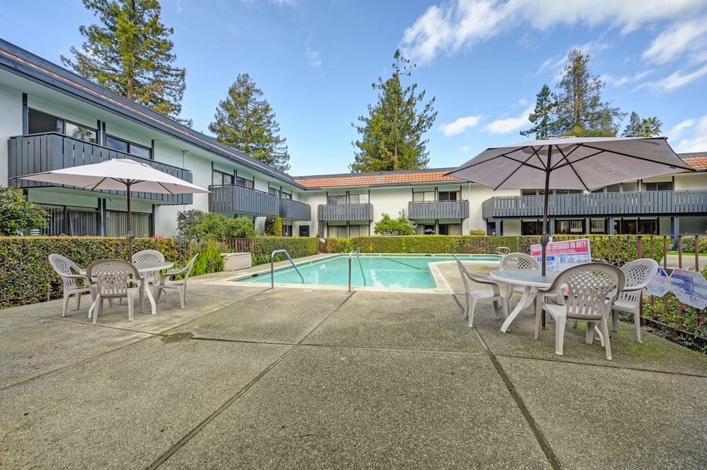 a swimming pool with tables and chairs and umbrellas