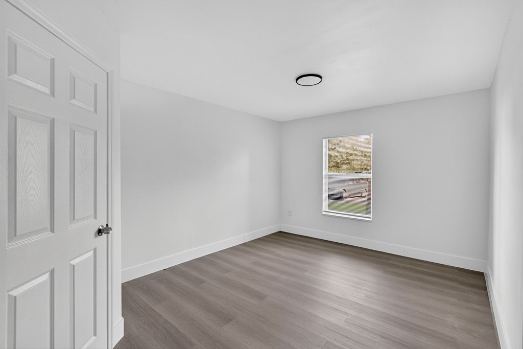 A room with a white door and a picture on the wall.