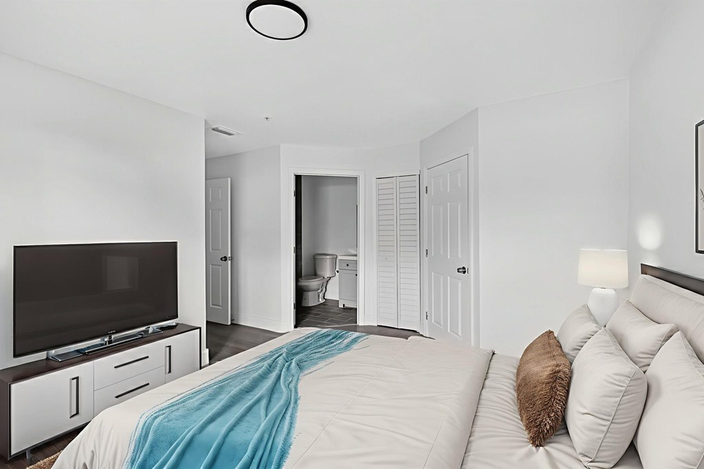 A bedroom with a bed, a television, and a mirror.