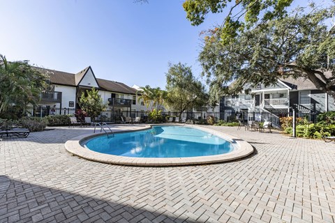 A swimming pool surrounded by a brick patio. at Foxcroft Apartments, Apartments, Tampa, FL