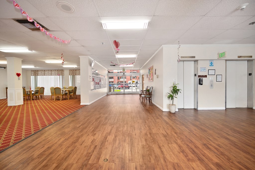 a large room with a wood floor and white walls and chairs and a red carpet