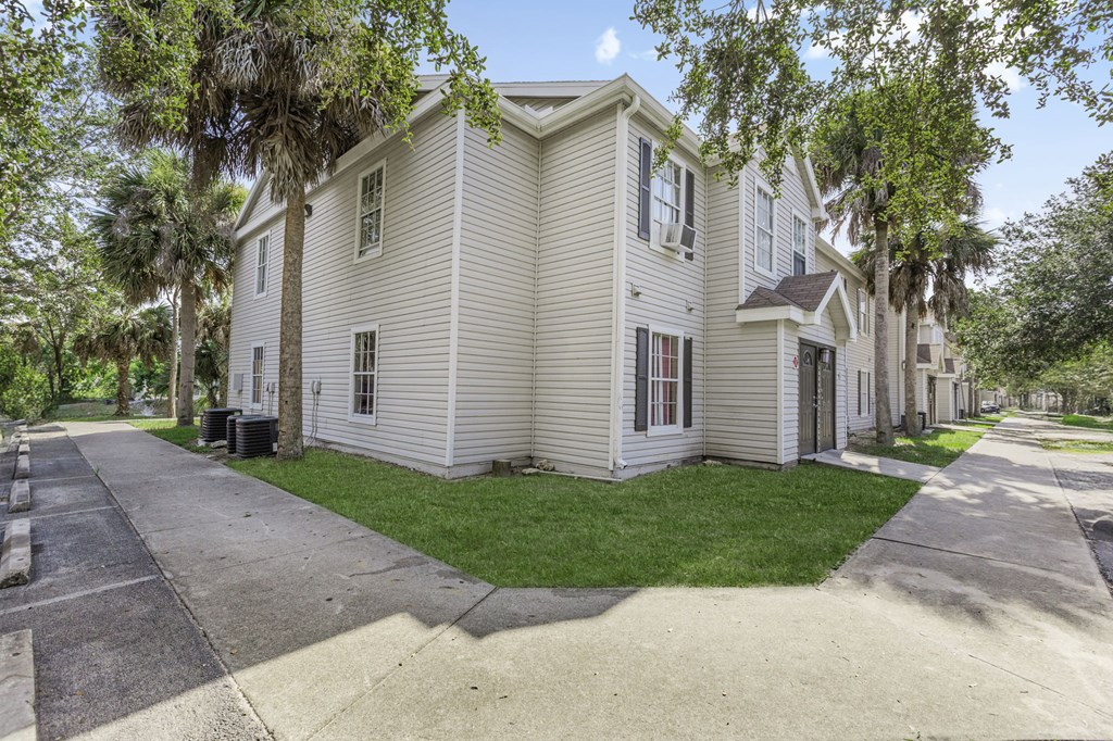 A white house with a green lawn in front.