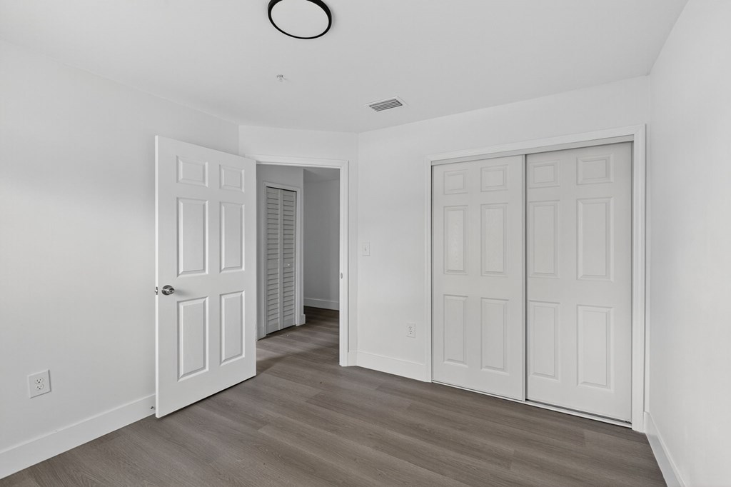 A room with two white doors and a light brown floor.