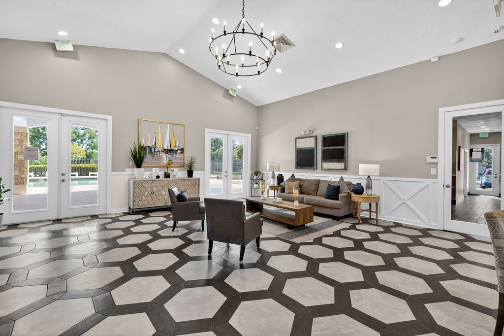 A spacious living room with a patterned floor and a chandelier.