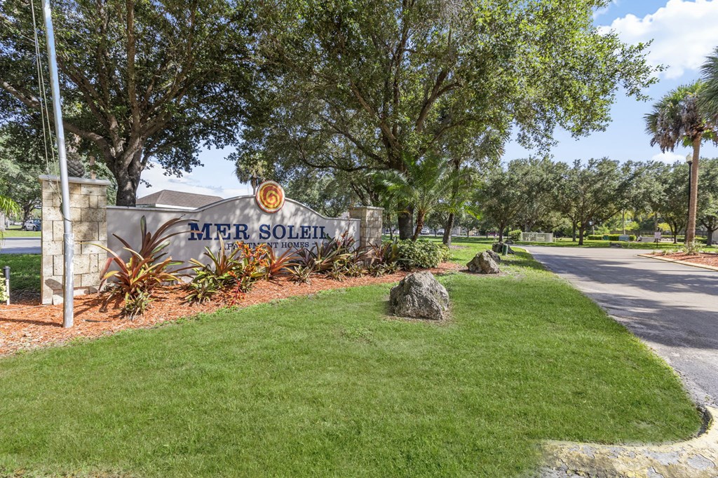 A sign that says "MER SOLEIL" is on a wall next to a grassy area.