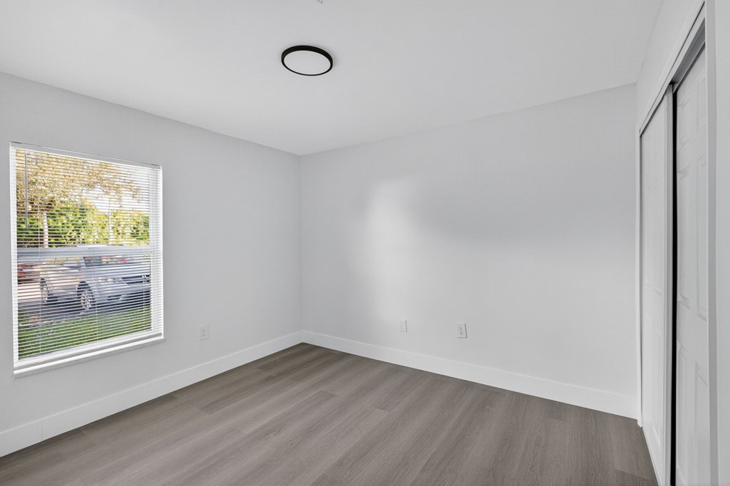 A room with a window showing a car and trees outside.