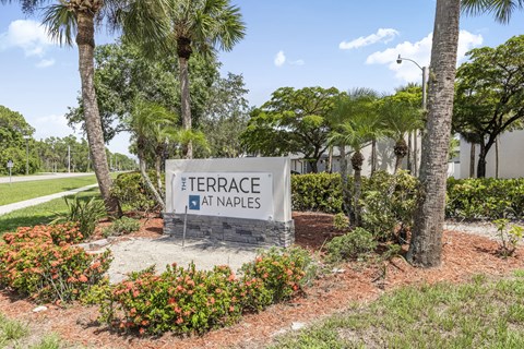 A sign that says Terrace at Naples in front of some trees.
