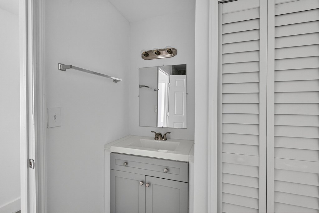 A white bathroom with a sink and a mirror.