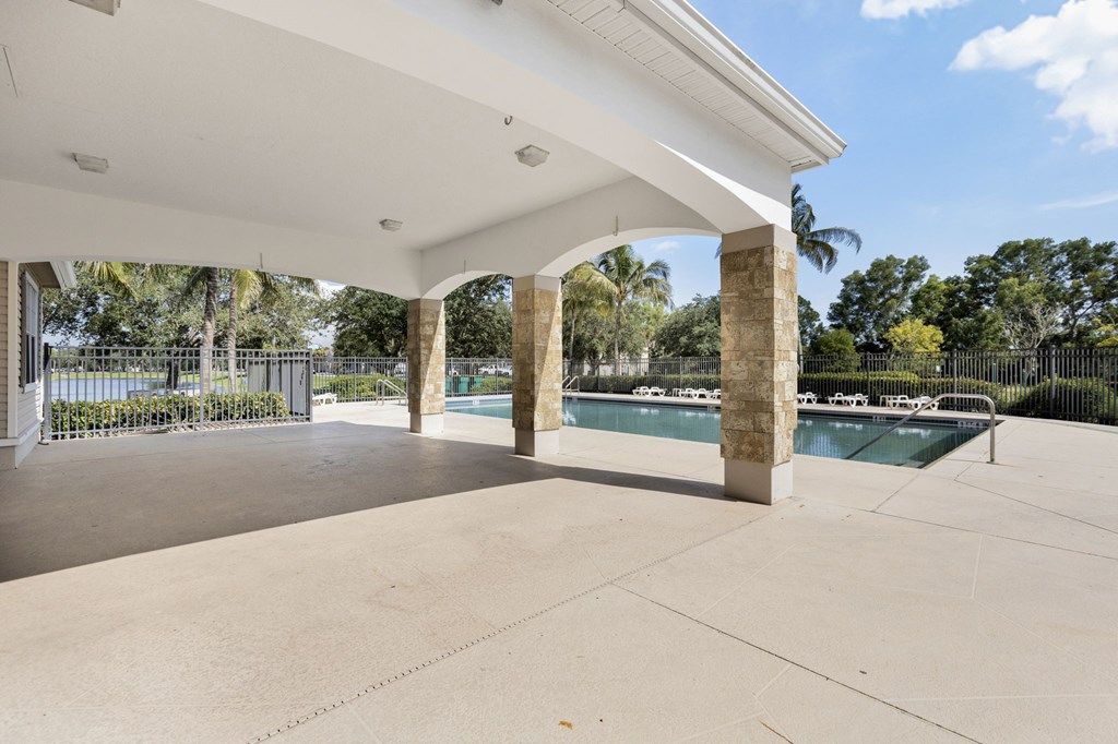 A pool area with a white roof and a concrete floor.